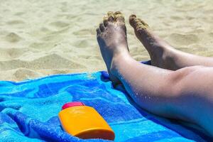 kvinna fötter och Solskydd rör på blå strand filt. foto