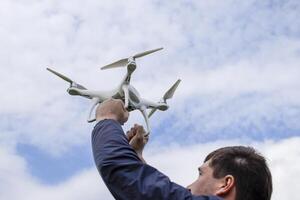 en man med en quadrocopter i hans vapen Uppfostrad till de himmel. en vit foto