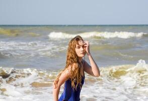 en blond flicka i en blå badning kostym på de strand. strand högtider. foto