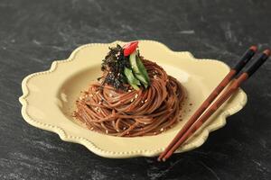 koreanska bovete spaghetti memil makguksu på grädde keramisk tallrik. foto