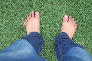 en person stående på gräs med deras bar fötter foto