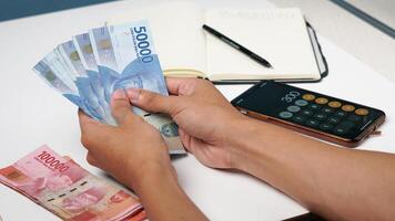 en man är räkning indonesiska rupiah sedlar. finansiell förvaltning begrepp foto