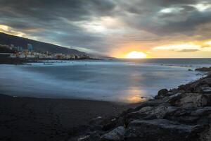 svart sten strand i puerto de la cruz förbi de solnedgång , teneriffa, kanariefågel öar Spanien foto