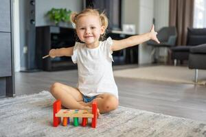 söt caucasian liten flicka spelar på de golv på Hem med eco trä- leksaker. montessori leksak. de barn spelar pedagogisk spel. foto