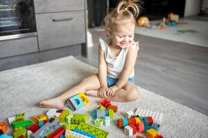 caucasian barn en liten flicka är spelar i de konstruktör på Hem. pedagogisk leksaker för barn. foto