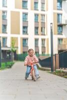 liten flicka ridning balans cykel i de gård av de bostad i Prag, Europa foto