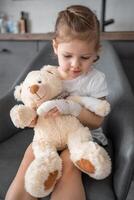 liten flicka med bruten finger innehar teddy Björn med en förbundit Tass på de läkares utnämning i de sjukhus foto