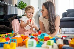 liten flicka spela med konstruktör leksak på golv i Hem med mamma eller kvinna barnvakt, pedagogisk spel, familj på Hem spendera fritid aktiviteter tid tillsammans begrepp foto