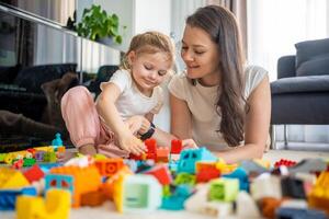 liten flicka spela med konstruktör leksak på golv i Hem med mamma eller kvinna barnvakt, pedagogisk spel, familj på Hem spendera fritid aktiviteter tid tillsammans begrepp foto