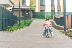 liten flicka ridning balans cykel i de gård av de bostad i Prag, Europa foto