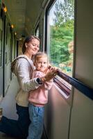 familj reser i en tåg och ser genom fönster. kvinna med barn reser förbi järnväg, Europa foto