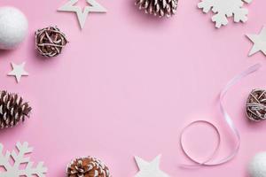 jul sammansättning på rosa skrivbord. vita stjärnor, bollar, snöflingor och kottar. jul bakgrund. ovanifrån, platt låg foto