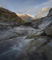 lugn vattenfall mitt i naturskön natur med majestätisk berg bakgrund. foto