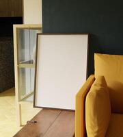 trä- ram attrapp affisch stående på de trä- bröst bredvid orange soffa i de minimalistisk levande rum foto