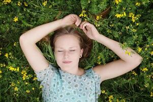 ung kvinna sovande i en blomma äng foto