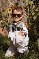 en liten pojke i ett astronaut kostym är spelar utanför på en solig dag. vertikal Foto. foto