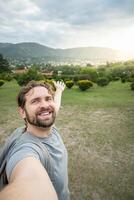 ung man tar en selfie i en skön natur parkera. foto