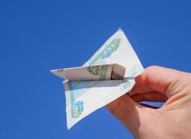 valörer av ryska pengar, vikta i de flygplan mot de blå himmel i hand foto