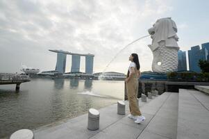 en kvinna i merlion fontän i främre av de marina bukt foto