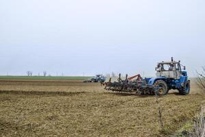 frodig och lossa de jord på de fält innan sådd. de traktor plogar en fält med en plog foto