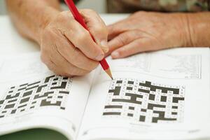 äldre kvinna spelar sudoku pussel spel för behandling demens förebyggande och alzheimers sjukdom. foto