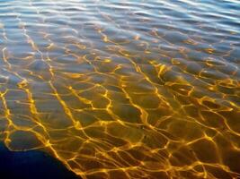 reflektioner av de Sol i vågor av transparent vatten. foto