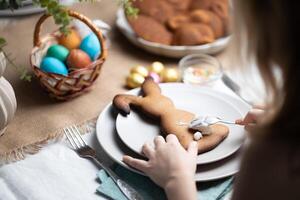 händer av barn dekorera pepparkaka småkakor med glasyr på festlig dekorerad tabell på påsk. Semester traditioner, familj tid foto