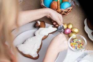 oigenkännlig barn garnering påsk kanin formad kaka med glasyr på festlig dekorerad tabell foto