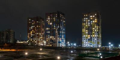med ljus i fönster av flervånings- byggnader på natt. liv i en stor stad. serenad av ljus foto