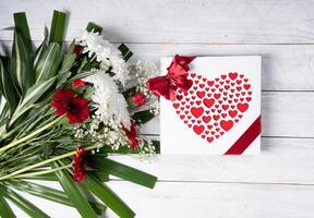 hjärtans dag gåva, röd hjärta pralin låda och blomma bukett på vit tabell foto