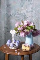 påsk kaka och målad ägg och en bukett av rosa sakura blommor på en tabell foto