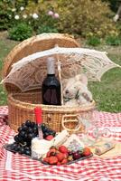 sommar picknick på en grön gräsmatta med röd vin, ost och färsk bär, vindruvor foto