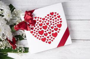 hjärtans dag gåva, röd hjärta pralin låda och blomma bukett på vit tabell foto