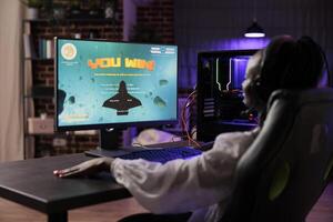 gamer fira vinnande uppkopplad multiplayer sf TV-spel passa ihop. afrikansk amerikan kvinna njuter ner tid på Hem, känsla nöjd handla om internet gaming mästerskap seger foto