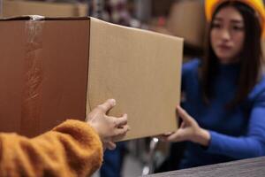 post service medarbetare innehav kartong låda i industriell lager. sändning företag anställda hantera kund paket leverans och framställning paket för leverans foto