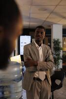 porträtt av afrikansk amerikan affärsman diskuterar företag vinst med medarbetare under arbete ha sönder i börja kontor. anställda arbetssätt sent på natt, planera investering strategi. företag begrepp foto