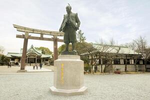 Osaka, Japan, 2023- toyotomi hideyosh staty i de osaka slott parkera område och trä- toriien Port med japansk helgedom på blå himmel. foto