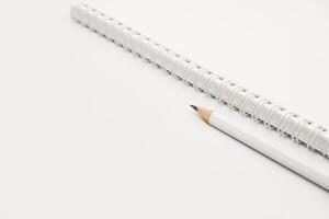tom vit spiral anteckningsbok med vit penna på säng. foto