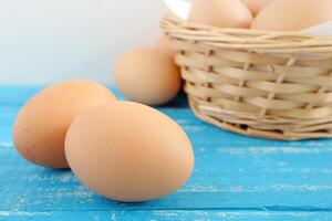 färsk kyckling ägg och ägg kartong på blå bedrövad trä- tabell foto
