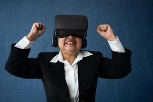 senior företag kvinna bär smart virtuell glasögon för video konferenser, vr headsetet glasögon teknologi i modern kontor och höja din vapen till visa Framgång. metavers begrepp. foto