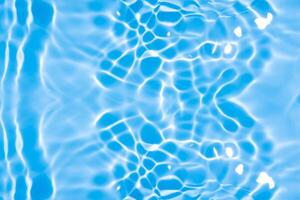 vatten yta. blått vatten vågor på de yta krusningar suddig. defokusering suddig transparent blå färgad klar lugna vatten yta textur med stänk och bubblor. vatten vågor med lysande mönster. foto