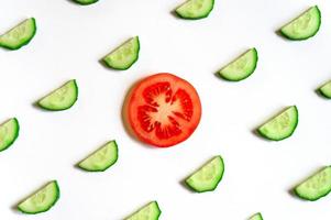 upprepande mönster av skivade halvcirklar av färska råa grönsaksgurkor för sallad och en skiva tomat foto