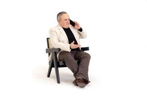 man Sammanträde i en stol och talande på de telefon på en vit bakgrund foto