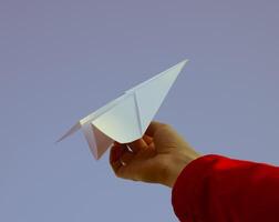 vit papper flygplan i hand mot de himmel. en symbol av frihet på de internet foto