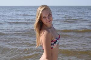 blond flicka i en bikini på de strand. skön ung kvinna i en färgrik bikini på hav bakgrund foto