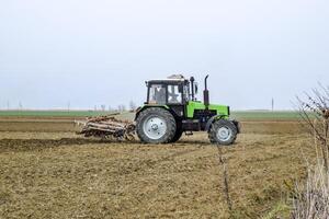 frodig och lossa de jord på de fält innan sådd. de traktor plogar en fält med en plog foto