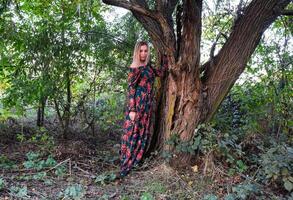 lady under en stor vide träd. kvinna i en klänning. foto
