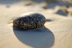 ai genererad en sten Sammanträde på topp av en sandig strand foto