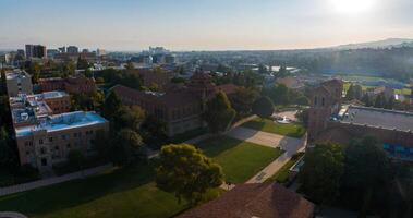 antenn se av historisk och modern universitet campus på soluppgång med grön gräsmattor och stadsbild bakgrund foto