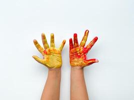 barns händer målad med gul och röd måla på vit bakgrund. foto